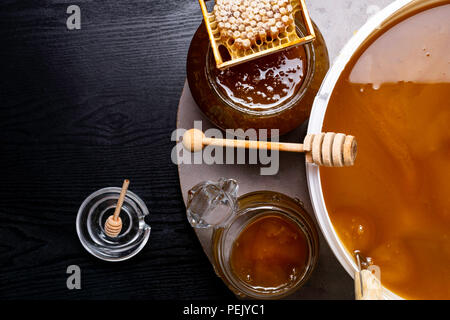 Le miel en pot et grand seau, honeycomb et bâton en bois Banque D'Images