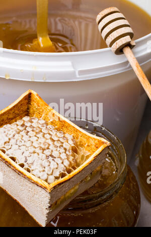 Le miel en pot et grand seau, honeycomb et bâton en bois Banque D'Images