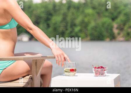 Portrait of a woman in a bikini atteindre pour un verre de champagne. Banque D'Images