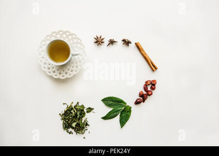 Une tasse de thé parfumé et utile. À proximité se trouvent divers ingrédients pour sa préparation. Banque D'Images