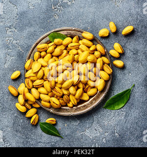 Pistaches jaune épicé de curcuma sur fond gris. Vue de dessus d'écrous. Banque D'Images