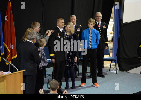 Le général de l'armée américaine, l'Al Dohrmann Dakota du Nord de l'adjudant général, se dresse sur une scène comme des membres de sa famille place sa promotion rang de général sur son uniforme au cours d'une cérémonie de promotion combiné et cérémonie de passation de commandement porter il assume la position de l'adjudant-général du major général David Sprynczynatyk, qui est debout à l'extrême droite, comme le général Frank Grass, chef de la Garde nationale, le troisième à partir de bureau droit, regarde à la Raymond J. Bohn Armory, Bismarck, N.D., 13 décembre 2015. (U.S. Photo de la Garde nationale aérienne capitaine principal Sgt. David H Lipp/libérés) Banque D'Images