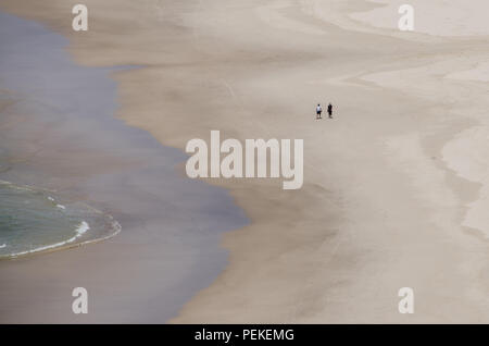 Deux personnes à pied au bord de l'eau sur la plage vide, Tallow Beach, Byron Bay, Nouvelles Galles du Sud, Australie. Des couples la solitude paisible sur le lonely beach . Banque D'Images