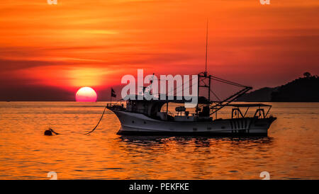 Vue paysage d'un coucher de soleil sur la mer de Chine du sud dans la région de Kota Kinabalu (Bornéo, Malaisie), avec un vieux bateau de pêche dans l'avant-plan Banque D'Images