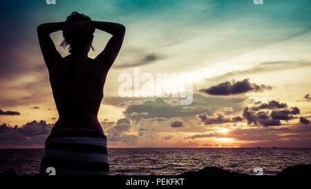 Vue paysage d'un coucher de soleil sur la mer de Chine du sud de Miri, avec la silhouette d'une belle jeune fille à l'avant-plan Banque D'Images