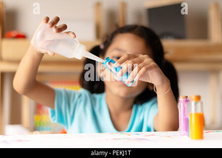 Asian girl est verser de l'eau dans un verre de couleur bleue à l'expérience. Sélectionnez l'accent faible profondeur de champ. Banque D'Images