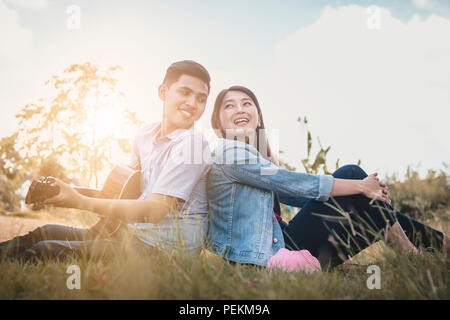 Image personnes asiatiques Thai love couple heureux, jouer de la guitare dans le parc. Banque D'Images