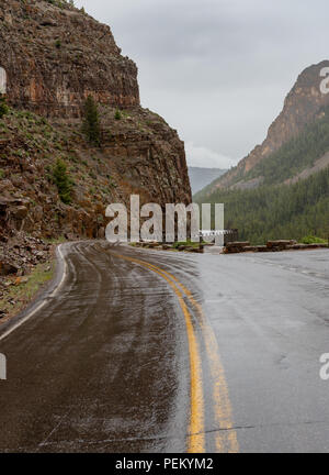 Route mouillée et Rock Cliff dans Yellowstone sur jour de pluie Banque D'Images