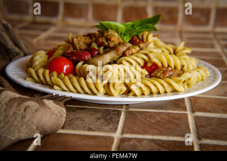 Rotinis italien pâtes en spirale dans la noisette sauce pesto au basilic avec les tomates raisins haricots saucisses et champignons Banque D'Images