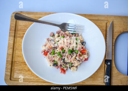 Salade de riz italien ou le riz froid dans une assiette blanche sur une planche avec fourchette et couteau. Banque D'Images