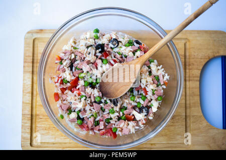 Salade de riz italien ou le riz froid dans une vitrine avec cuillère woodden sur une planche avec un fond blanc. Banque D'Images