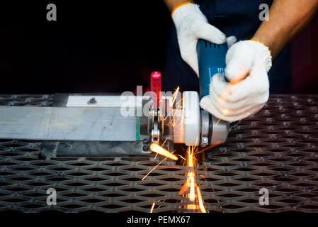 Worker cutting avec broyeur et le métal de soudure avec beaucoup d'étincelles sharp en usine Banque D'Images