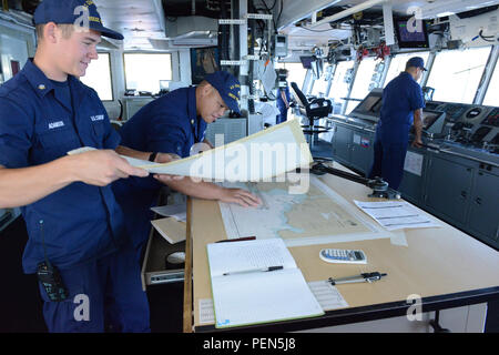 Maître de 3e classe Stanley Adamson et maître de 1re classe Silvestre Suga, les deux compagnons d'une sellette à bord de piste, Noyer USCGC la position du navire via les cartes papier pendant le transit, Kauai en mer le 4 décembre 2015. Noyer et d'un des six membres de l'équipe de plongée plongée Régional Pacifique Casier ont travaillé ensemble pour mener des opérations de récupération des aides à la navigation bouées près de l'eau haut-fond. (U.S. Photo de la Garde côtière canadienne par le maître de 3e classe Melissa E. McKenzie/libérés) Banque D'Images