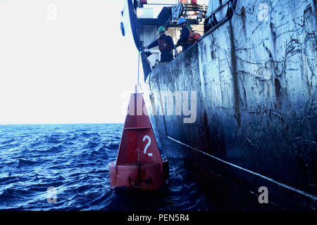 Membres d'équipage à bord d'une bouée USCGC Noyer se préparer à être pris en remorque par un 24 pieds d'aides à la navigation en mer Boat-Large Cutter Kauai, le 4 décembre, 2015. Les plongeurs de plongée Régional Pacifique Casier Noyer assistée conduite opérations de récupération des aides à la navigation bouées près de l'eau haut-fond. (U.S. Photo de la Garde côtière canadienne par le maître de 3e classe Melissa E. McKenzie/libérés) Banque D'Images