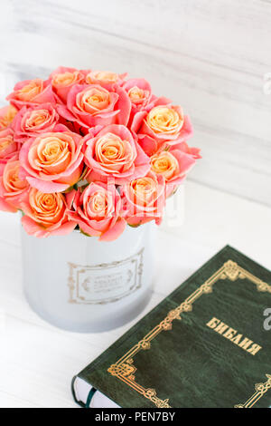 Roses dans une boîte ronde et la Bible. Belles roses roses sur un fond de bois blanc. Belles roses et la Bible. Roses dans une boîte à chapeau Banque D'Images