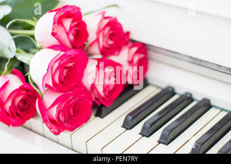 Roses rouges de luxe sur un piano. Bouquet de roses rouges et des touches de piano Banque D'Images