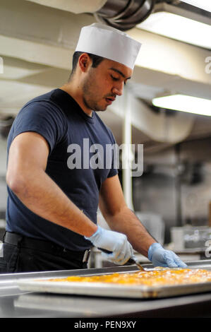 160103-N-GJ630-054 Yokosuka, Japon (Janv. 03, 2016) 3ème classe spécialiste culinaire Nestor Gonzalez, de Colchester, Connecticut), fait un peach crisp dessert à la boulangerie de la Marine américaine est que l'avant-déployé porte-avions USS Ronald Reagan (CVN 76). Ronald Reagan fournit une force prête au combat qui protège et défend les intérêts collectifs des maritimes des États-Unis et de ses alliés et partenaires dans la région Asie-Pacifique Indo-Asia. (U.S. Photo par marine Spécialiste de la communication de masse 2e classe Dave Frederick/libérés) Banque D'Images