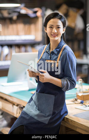 Confiant la tenue d'une artisane du cuir digital tablet in studio Banque D'Images