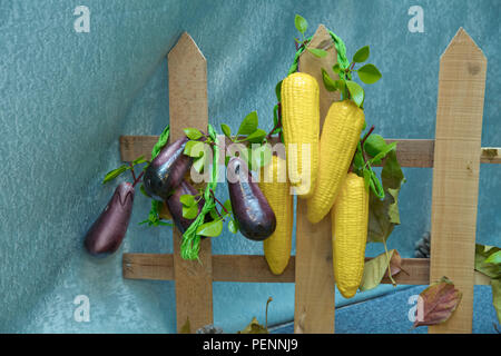 Clôture en bois . Maïs artificiel et l'aubergine. Fruits et légumes artificiels sur un fond bleu Banque D'Images