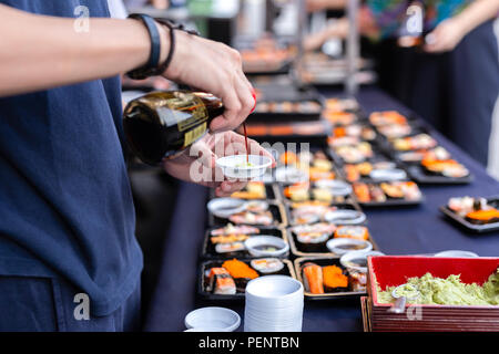 La main mise au point sélectionné pouring sauce wasabi sushi avec la Thaïlande sur les sushis japonais rue événement. Banque D'Images