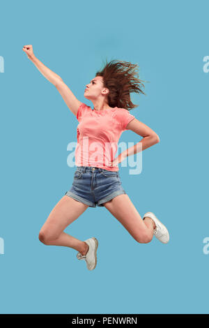 La liberté en déménagement. Déplacez uniquement vers l'avenir. jolie jeune femme sautant et gesticulant contre studio bleu arrière-plan. Shining girl en mouvement ou mouvement. Les émotions humaines et les expressions faciales concept Banque D'Images