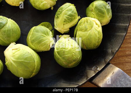 Composition des choux de bruxelles frais dans une poêle de fer sur une planche en bois Banque D'Images