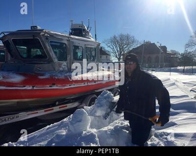 Maître de 1re classe Ty Coulter, un membre de l'équipage de la Garde côtière à Sandy Hook, N.J., pelles neige entourant la garde côtière un bateau d'intervention de 25 pieds - petit, le 24 janvier 2016. Une énorme tempête ébranlé le milieu de l'Atlantique et de la côte Est le 23 janvier 2016, la production de neige généralisée de plus de deux pieds dans la plupart des régions. (U.S. Photo de la Garde côtière du Maître de 2e classe Richard Clarke, III) Banque D'Images