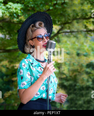 Jayne Darling, chanteuse féminine, chantant devant un microphone vintage devant la foule au Crich Tramway Village, 1940s événement. Banque D'Images