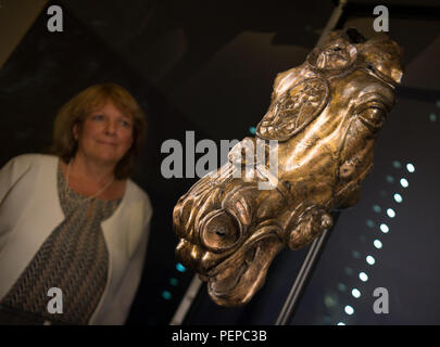 Bad Homburg, Allemagne. Août 17, 2018. Restaurateur Angelika Ulbrich se penche sur les quelque 2000 ans tête de cheval antique de Waldgirmes, qui est exposé dans une vitrine dans le fort romain Saalburg près de Bad Homburg. La tête de cheval en bronze doré a été trouvé lors de fouilles archéologiques dans Lahnau-Walgirmes dans le centre de Hesse en 2009 et a été entièrement restauré. La précieuse sculpture a été l'objet de plusieurs années de procès. (Dpa "Roman sur la tête de cheval à Saalburg voir' à partir de 17.08.2018) Crédit : Arne Dedert/dpa/Alamy Live News Banque D'Images