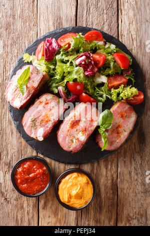 Poitrine de porc grillé et salade fraîche sont servis du ketchup et de la moutarde sur la table. Haut Vertical Vue de dessus Banque D'Images
