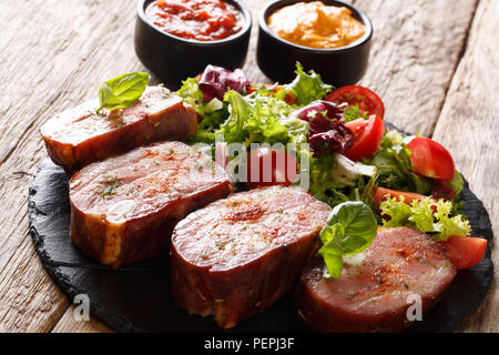 Côtes de porc fumé et salade de légumes frais sur une plaque en ardoise avec du ketchup et de la moutarde. Banque D'Images