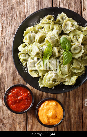 Vert épinards savoureux cappelletti, ravioli, tortellini avec le fromage, le basilic, du ketchup, de la moutarde gros plan sur la table. Haut Vertical Vue de dessus Banque D'Images