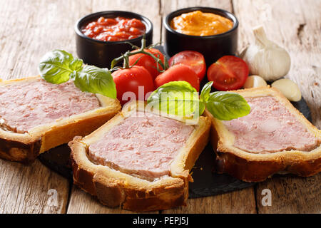 Brioche en tranches de porc farci aux légumes terrine déposée et sauces sur la table close-up horizontale, rustique. Banque D'Images