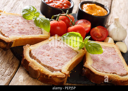 Terrine, pâté français dans une brioche servi avec des légumes et des sauces sur la table. à l'horizontal, style rustique Banque D'Images