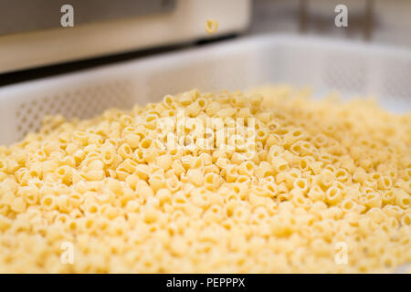 Mini pâtes penne d'être coupées à l'aide d'une matrice de découpe. Banque D'Images