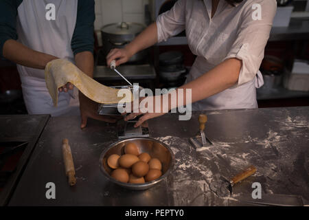 Les boulangers de l'utilisation de la machine pour la préparation de pâtes dans une boulangerie Banque D'Images