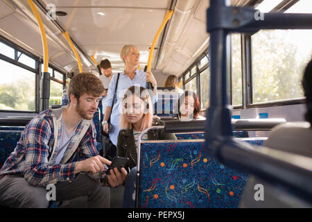 Couple à l'aide de téléphone portable en voyage en autobus moderne Banque D'Images