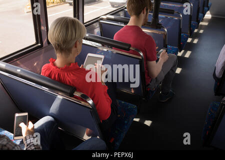 Banlieue femelle using digital tablet lors des déplacements en autobus moderne Banque D'Images
