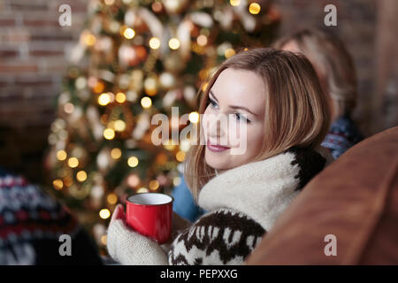 Les jeunes professionnels les amis de boire du vin alors qu'il était assis près de l'arbre de Noël décoré en loft Banque D'Images