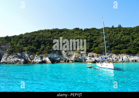 Vue imprenable sur la mer bleue à Antipaxos, Grèce. Arbres tout autour et deux bateaux sur l'eau. Un coup d'été totalement ! Banque D'Images