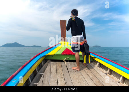 Homme debout sur le bateau avec matériel de plongée à l'île tropicale en vacances. Banque D'Images