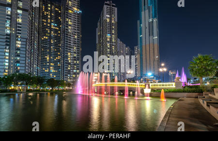 Un état de l'art fontaine de nuit avec des lumières colorées, chatoyantes derrière les gratte-ciel dans le développement du parc urbain Banque D'Images