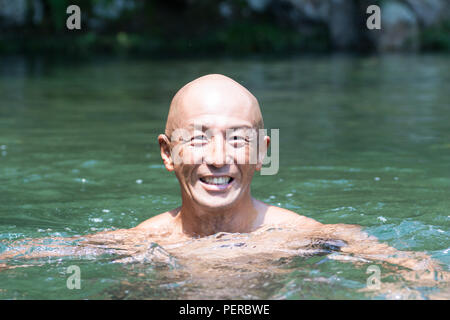 Smiling Japanese bald head guy trempées dans l'eau Banque D'Images