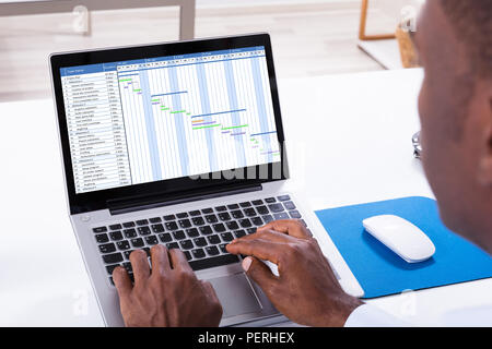 Close-up of a woman avec diagramme de Gantt sur l'ordinateur portable sur le bureau Banque D'Images