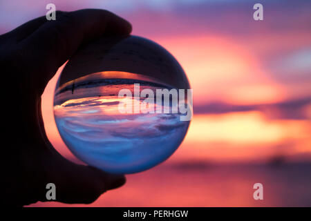 Rose et violet coucher de soleil sur l'océan pris par bille de verre Banque D'Images
