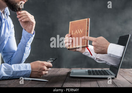 L'homme est à la recherche à la mains sortant de l'ordinateur portable qui est titulaire d'un livre sur la loi. Métaphore de la loi dans l'internet Banque D'Images