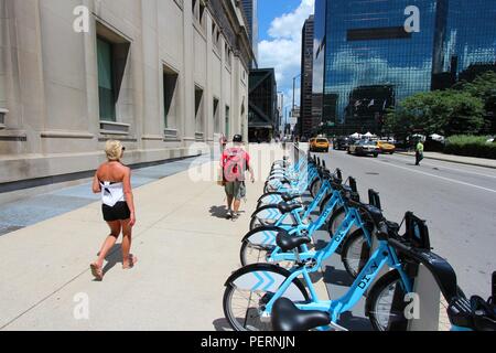 CHICAGO - le 28 juin : Les gens passent devant la gare de partage de vélos le 28 juin 2013 à Chicago. Partager vélos ont 300 stations de partage et de l'achalandage quotidien Banque D'Images