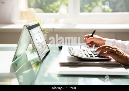 Close-up of a businessman's hand calcul calculatrice à l'aide de la facture Banque D'Images