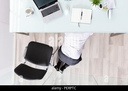 Portrait of se cachant sous Desk In Office Banque D'Images