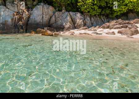 Vue de la partie rocheuse de Rawa beach avec son sable fin et blanc, l'ombre des arbres et des poissons nageant dans les eaux peu profondes de cette éblouissante belle... Banque D'Images